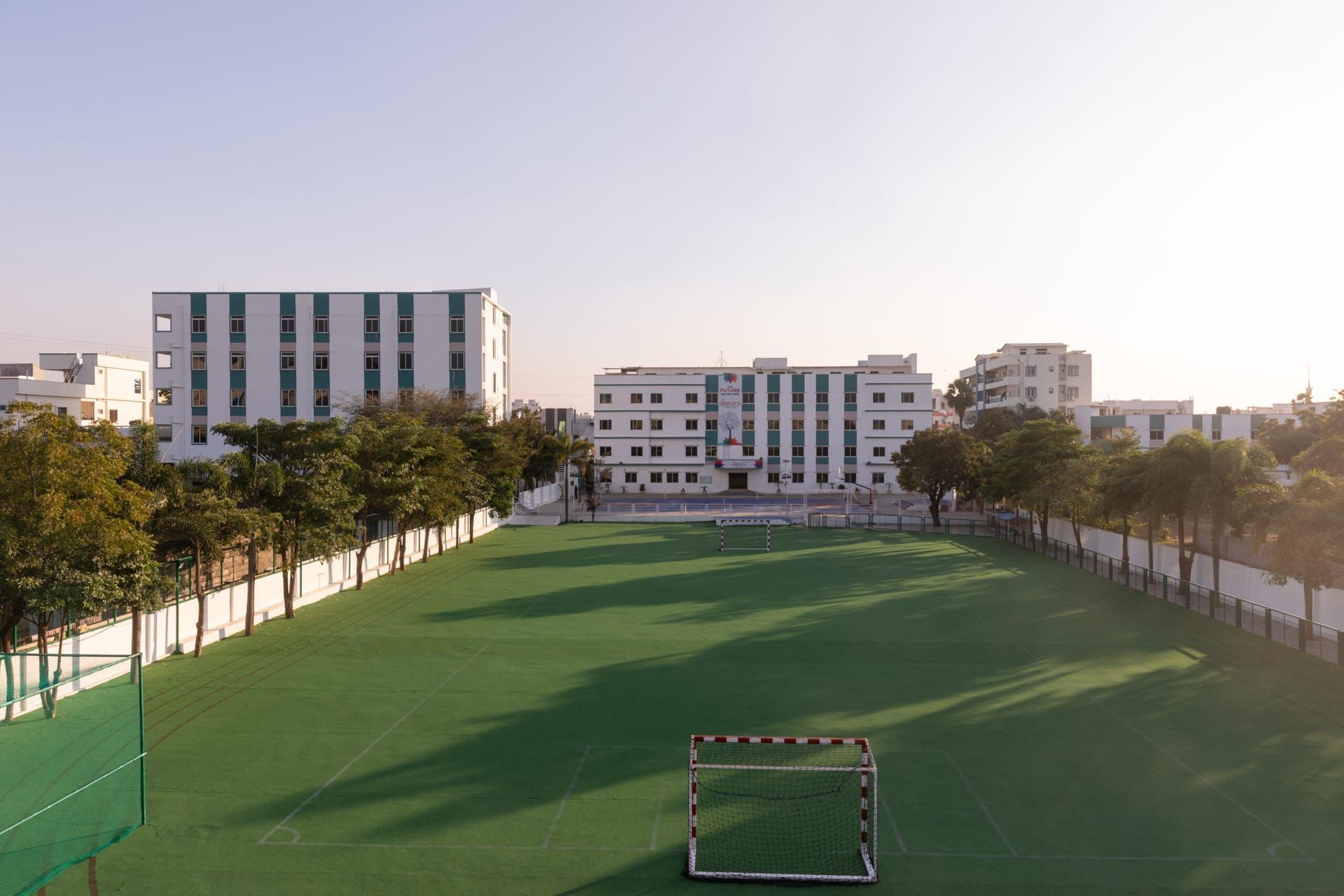 Green football ground and school buildings at sunset